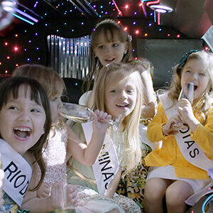 Child beauty contestants sit in a limousine